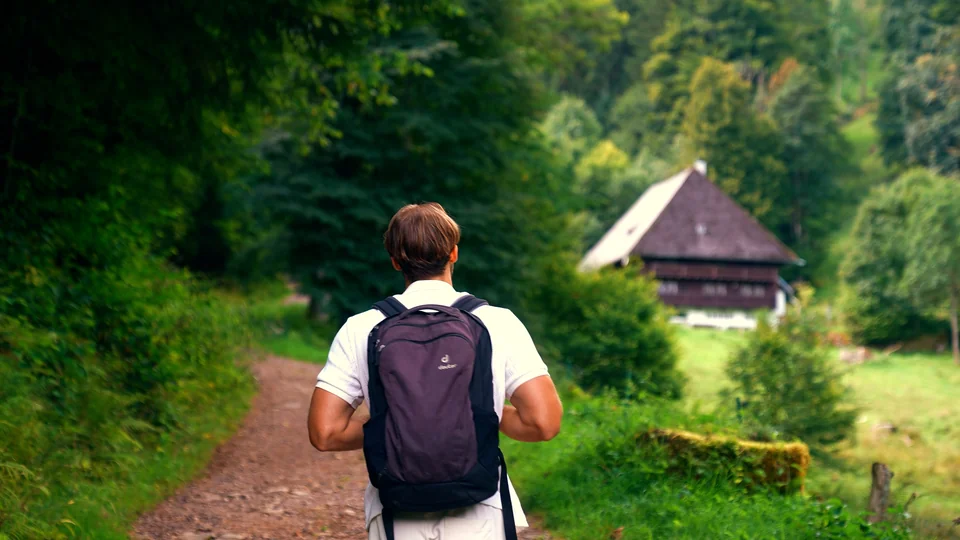Pjotr Weiss geht mit einem Rucksack auf einem Waldweg.